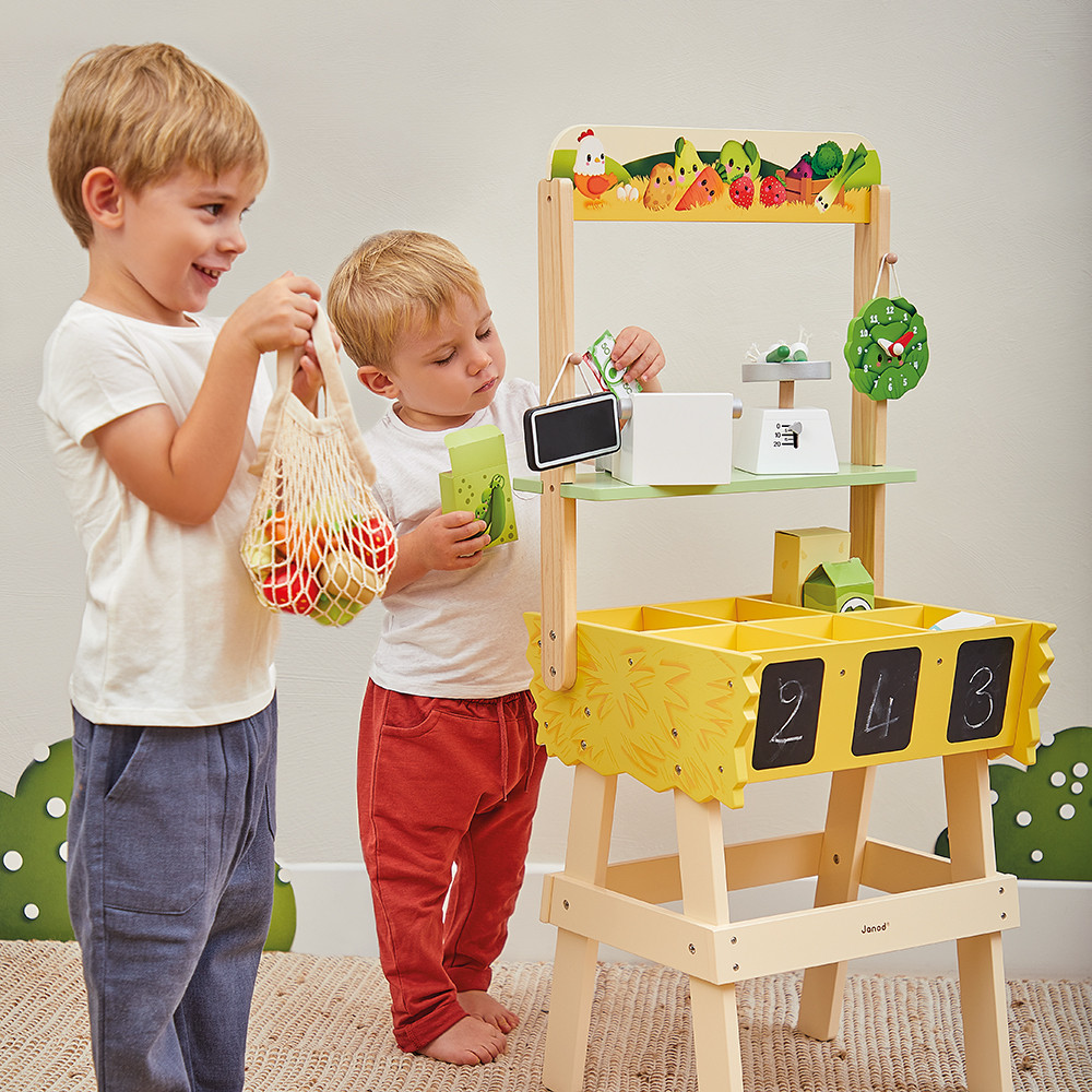 Enfants jouant avec la Marchande Farm Market, jouet d'imitation en bois JANOD